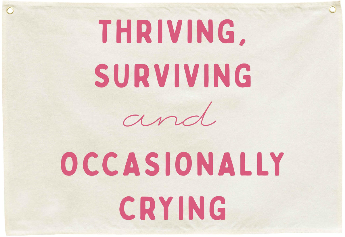Sioial Thriving Surviving beige banner; easy to hang above crib.