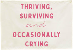 Sioial Thriving Surviving beige banner; easy to hang above crib.