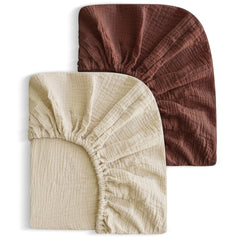 SNOOZYNEST two-pack muslin crib sheets in cedar and cream, soft and breathable.