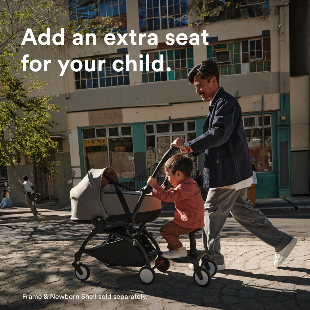 Child sits or stands on the Stokke YOYO Board during a city stroll.