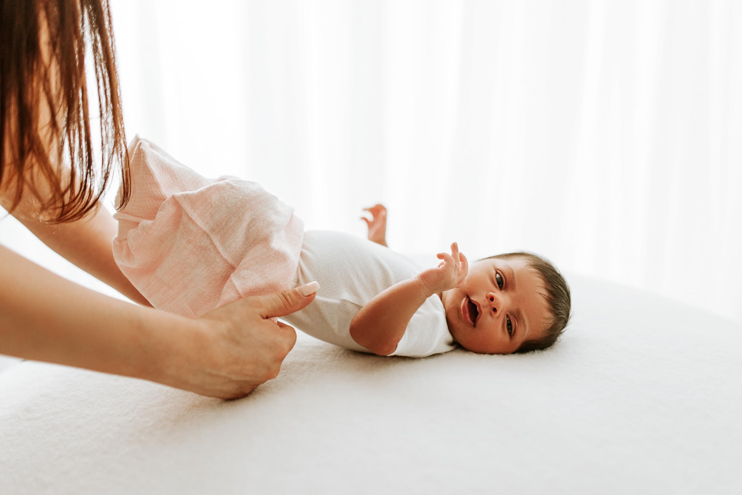 Swaddelini Swaddle Sleep Sack Pink baby in bed highlights moisture-wicking for dry nights.