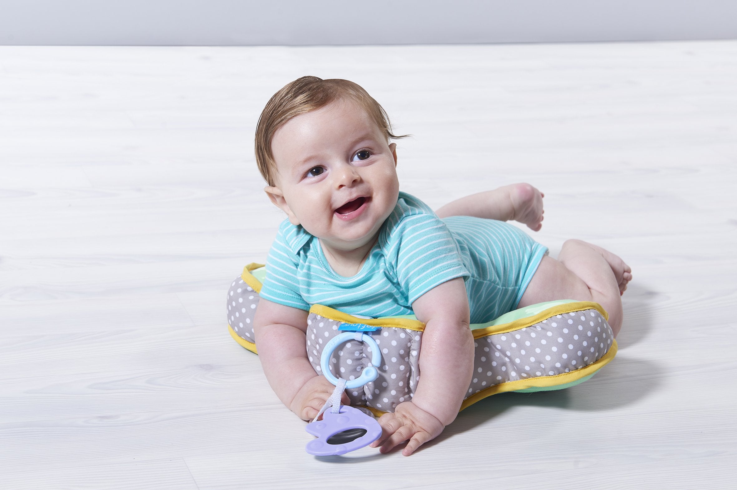 Taf Toys tummy time cushion demonstrates ergonomic chest support for gentle lifting.