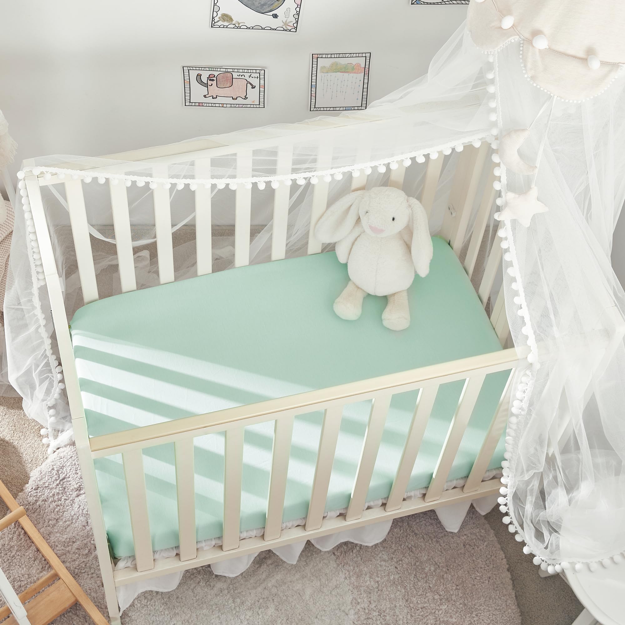 TILLYOU mini crib fitted sheet in light green on a compact mattress with snug fit.