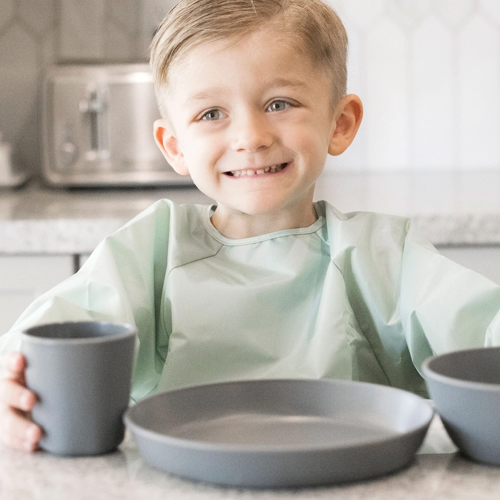Waterproof smock bib by Tiny Twinkle in sage charcoal for mess-prone meals.
