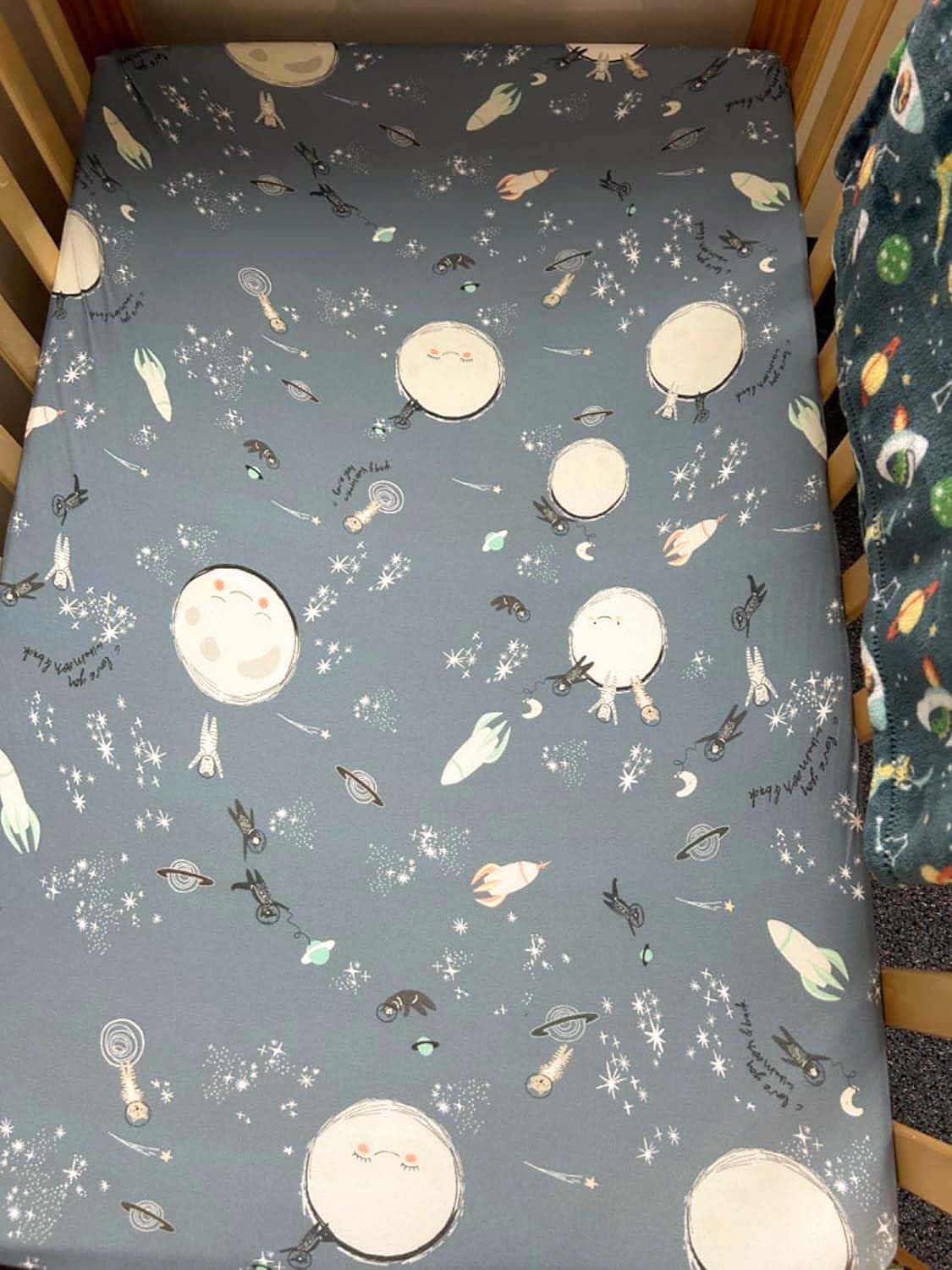TotAha Space sheet in use on crib bed, baby resting peacefully