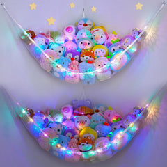 Unicorn Castle hammock with LED light holding stuffed animals in a bright kids' room.