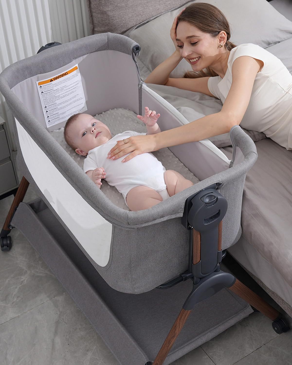 Winchild baby bassinet gray bedside sleeper with secure side attachment for night soothing.