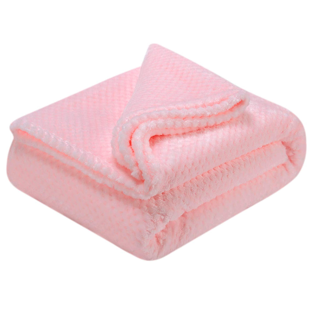Wonder Miracle fuzzy throw blanket in baby pink folded beside cushions for versatile home comfort.