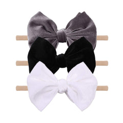 YanJie velvet bow on a black headband showing soft texture and gentle padding for newborns